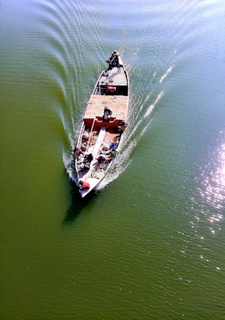 A calm river with a sturdy boat carrying crates of food supplies towards a remote village.