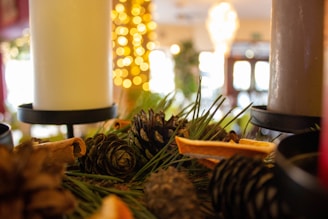 Close-up of rustic candle holders surrounded by dried leaves and pinecones.