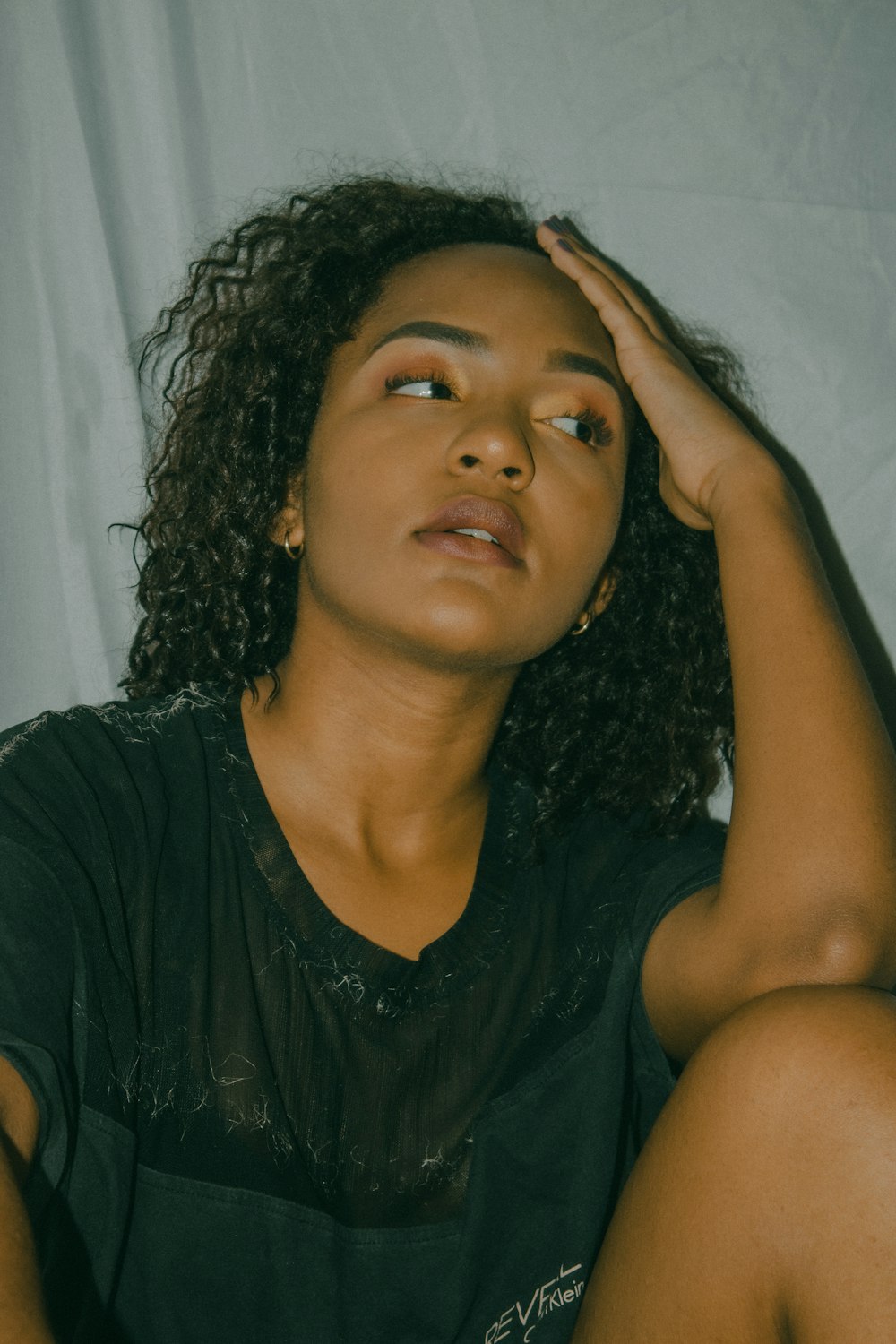 a woman sitting on a bed with her hand on her head