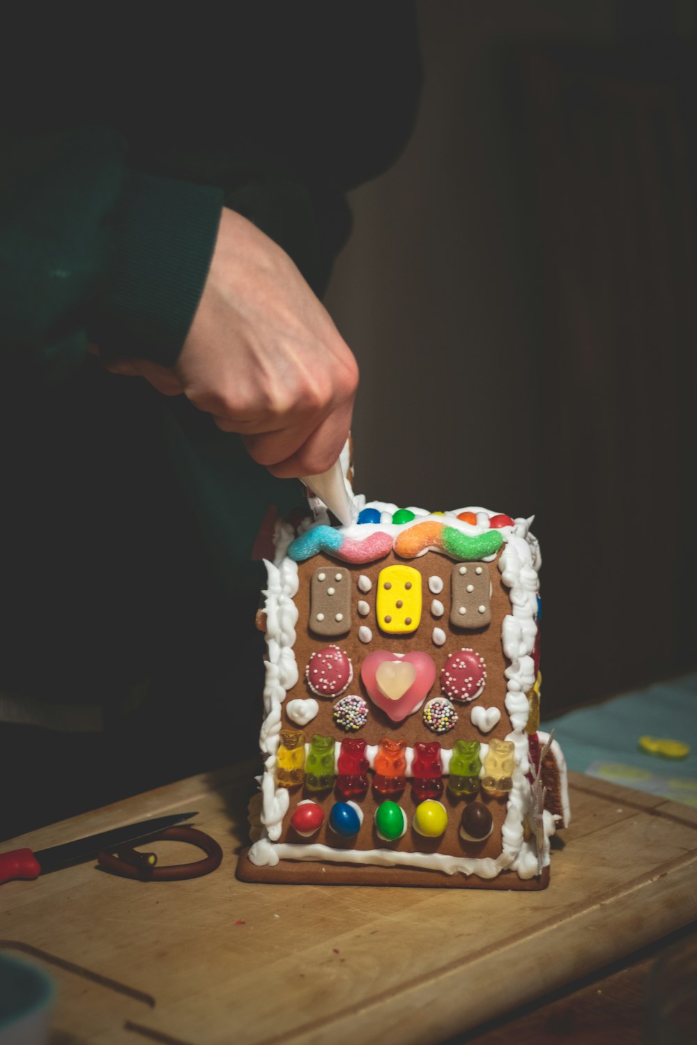 a person decorating a gingerbread house with icing