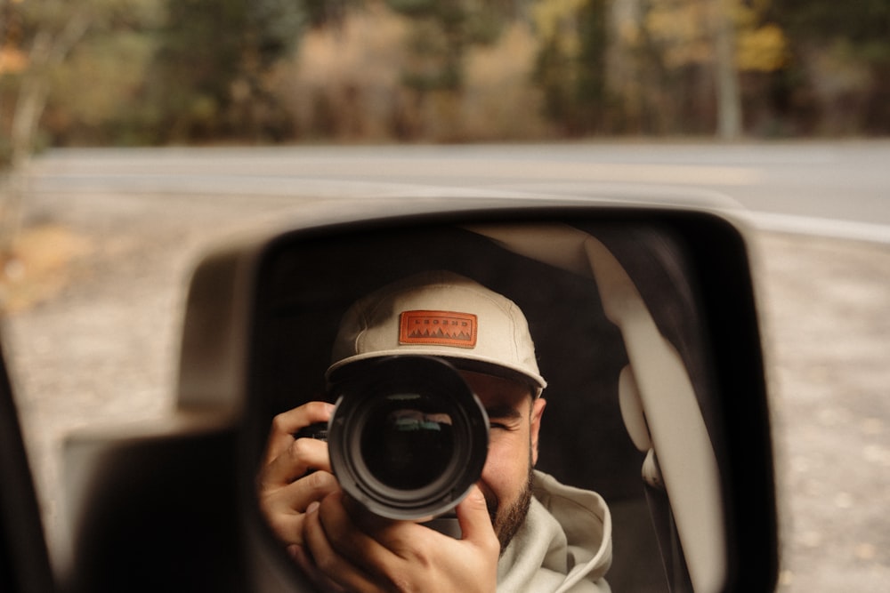 a man taking a picture of himself in a car mirror