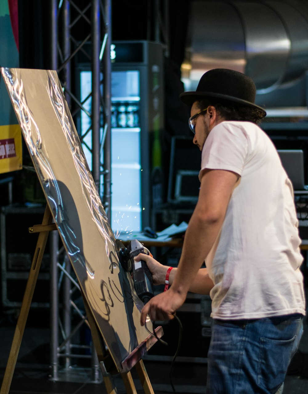 a man standing next to a easel with a painting on it