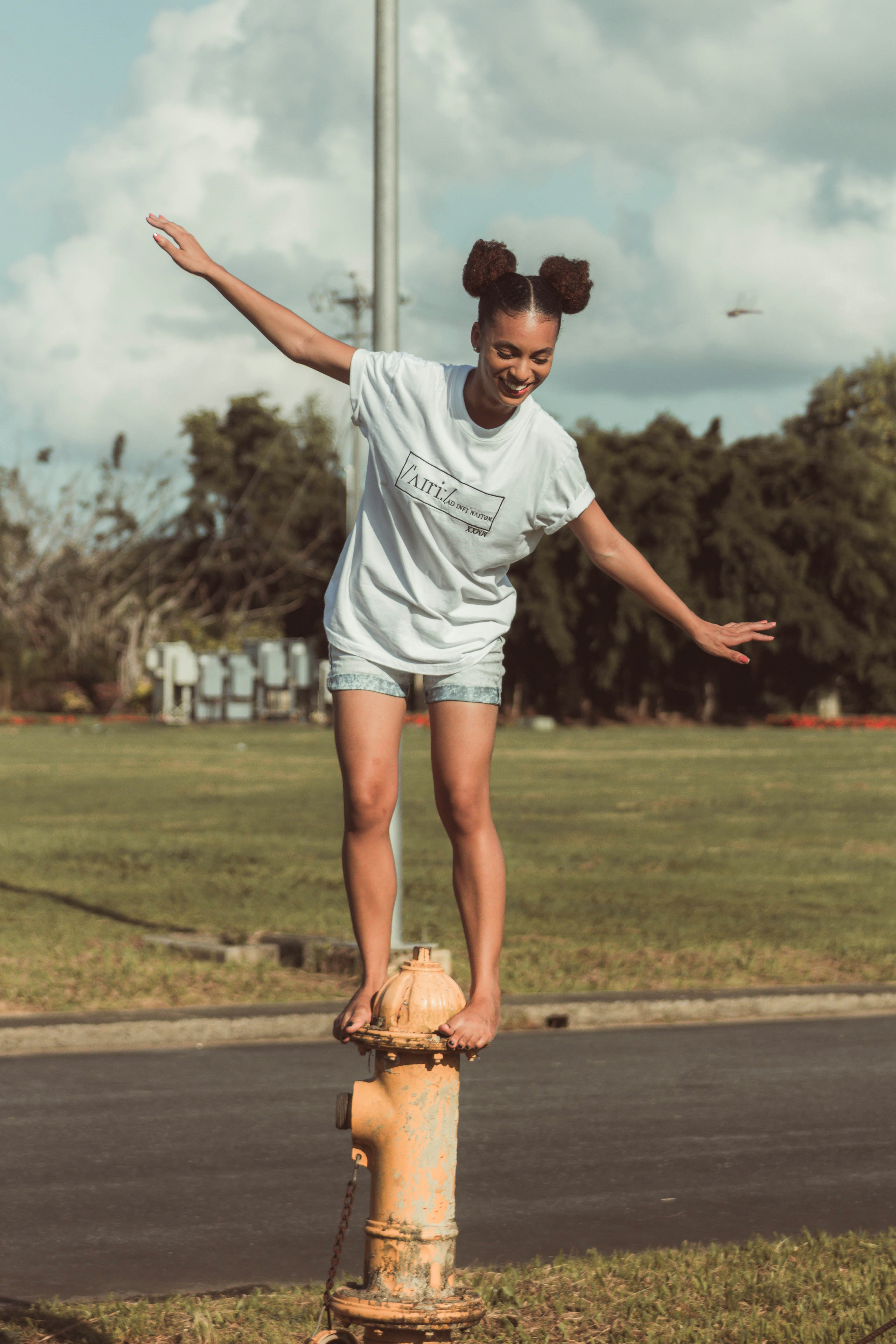 a girl is standing on top of a fire hydrant