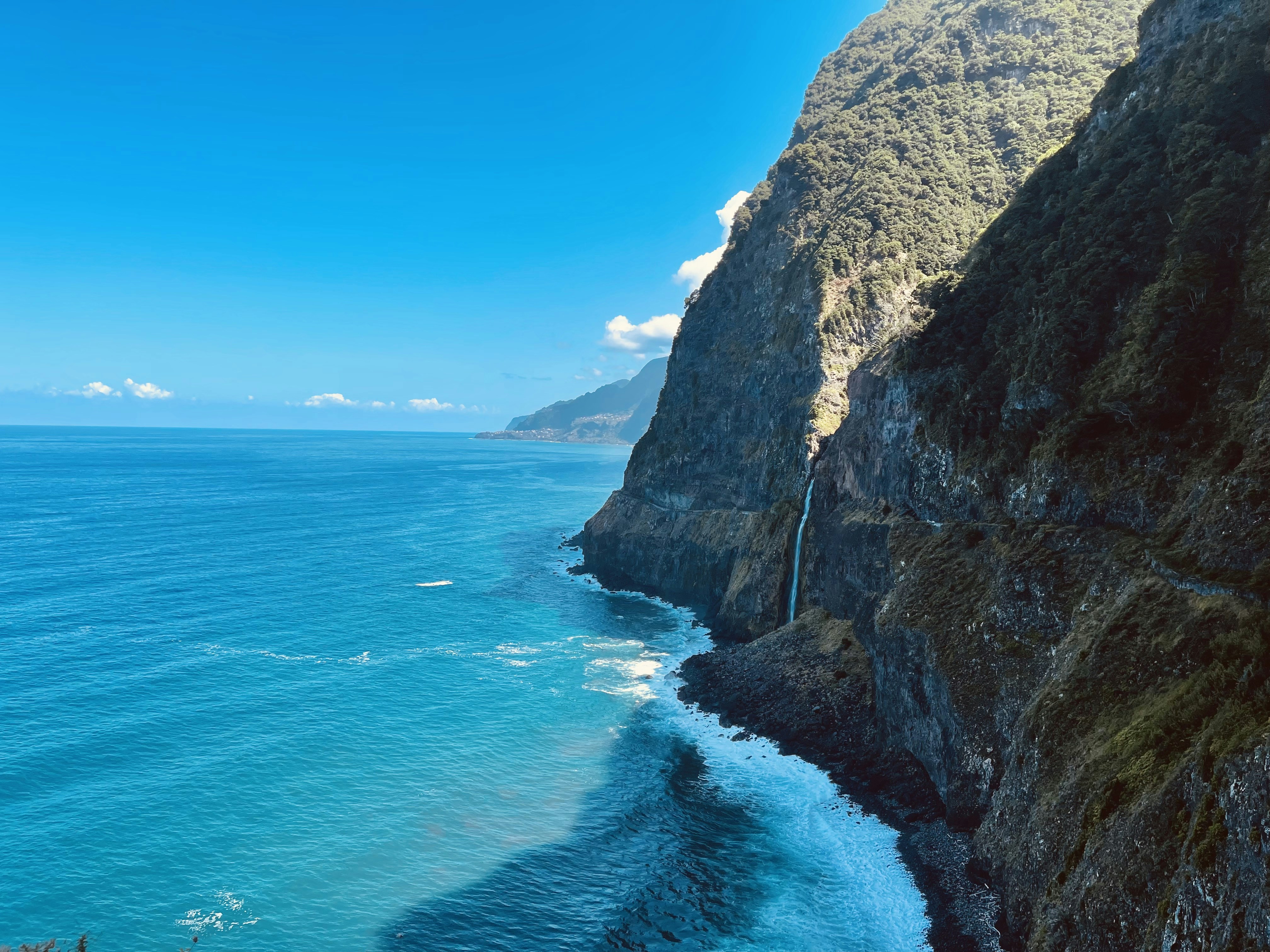 A breathtaking view of Bali's stunning coastline at sunset with lush greenery and vibrant blue waters.