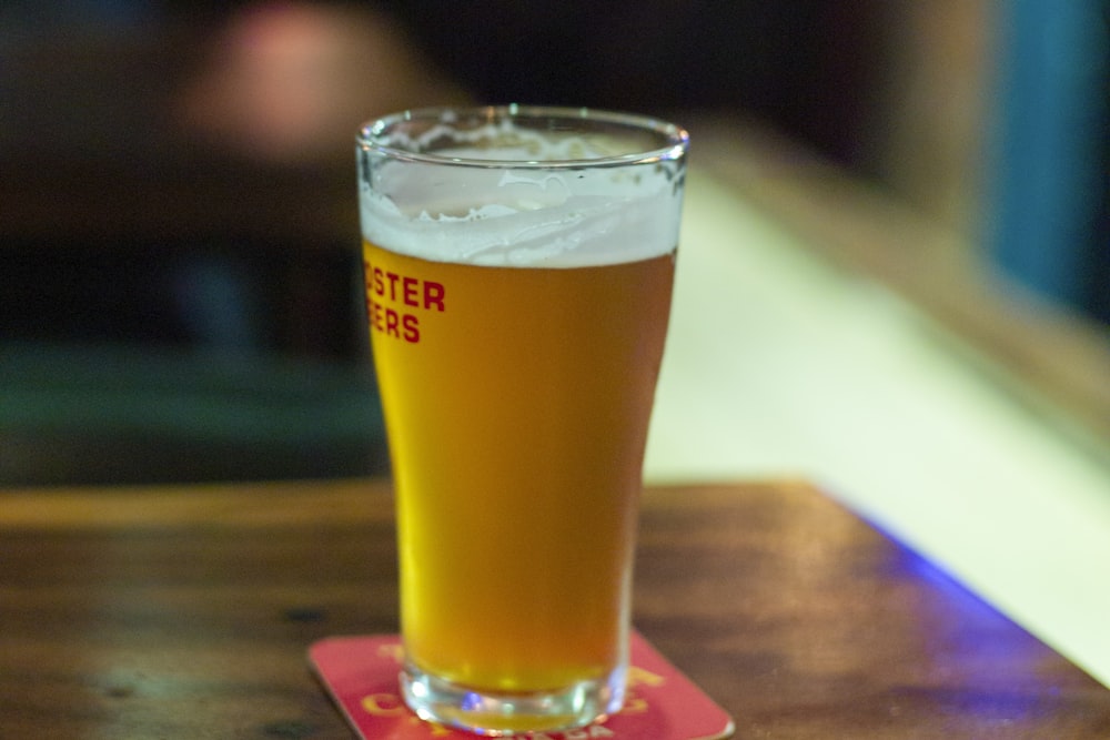 a glass of beer sitting on top of a wooden table