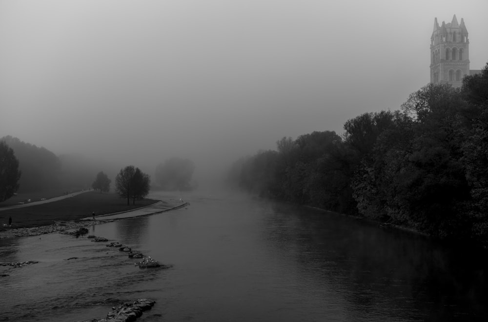 a black and white photo of a river with a church in the background