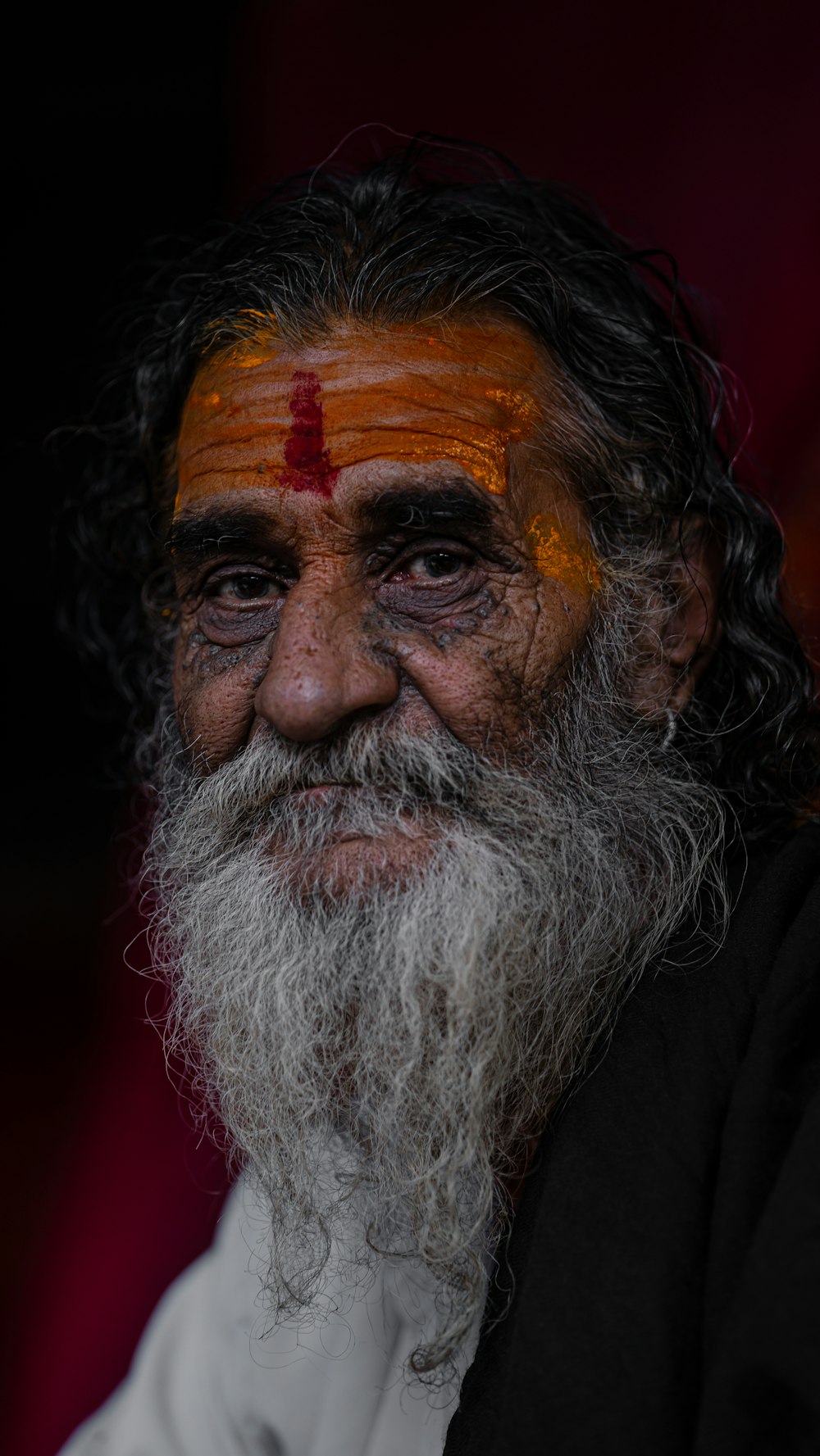 Un homme avec une barbe blanche et une croix rouge sur le front