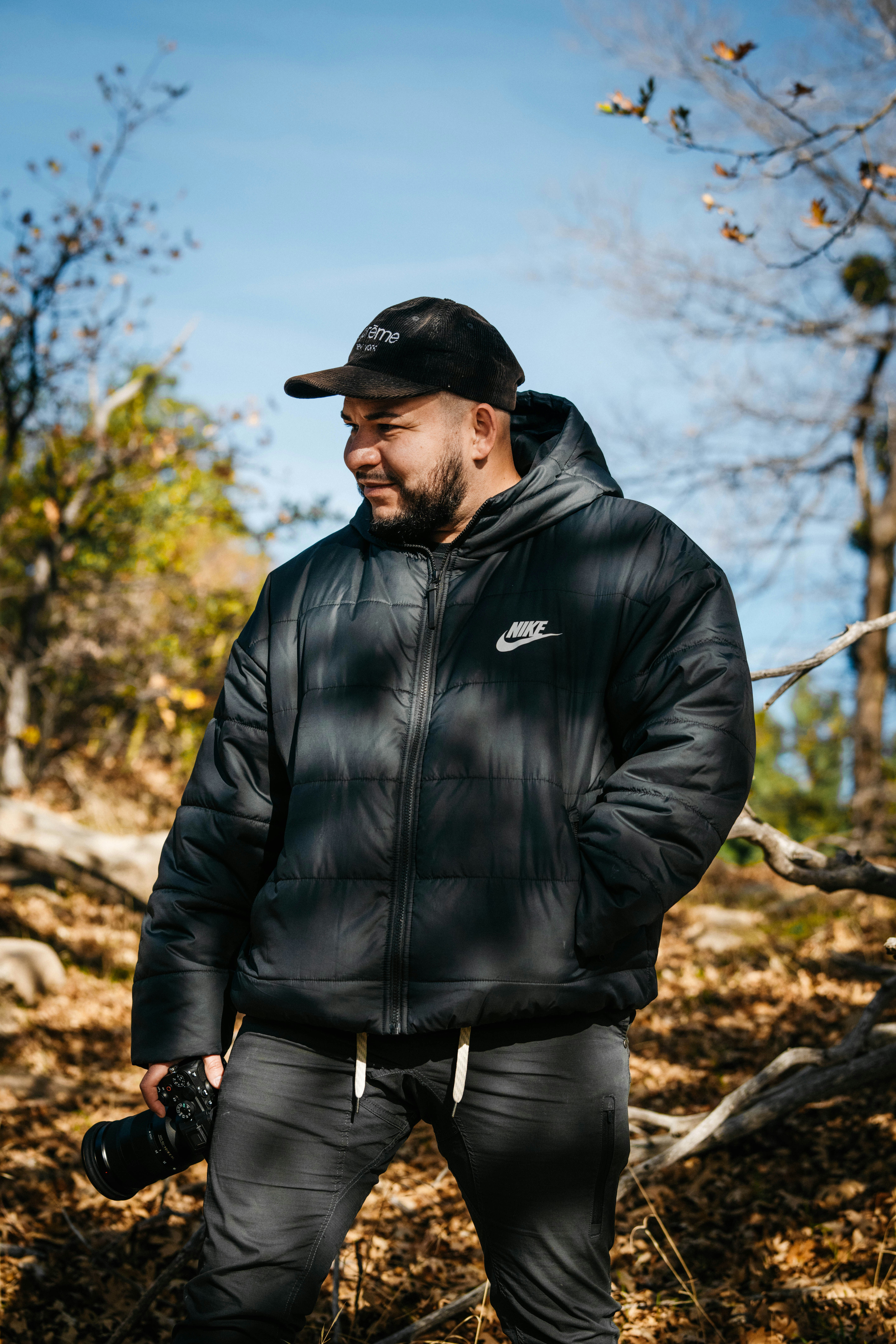 검은 재킷과 모자를 쓴 남자가 카메라를 들고 있다