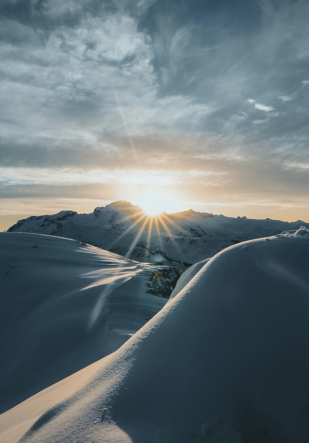 the sun is setting over a snowy mountain