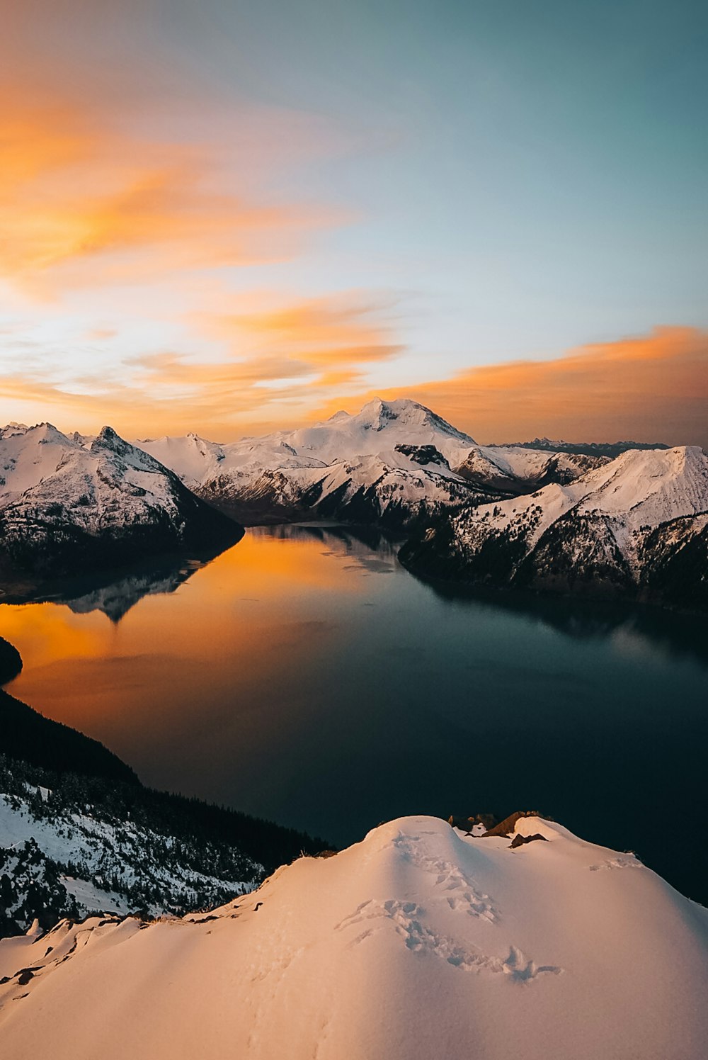 a view of a lake surrounded by snow covered mountains