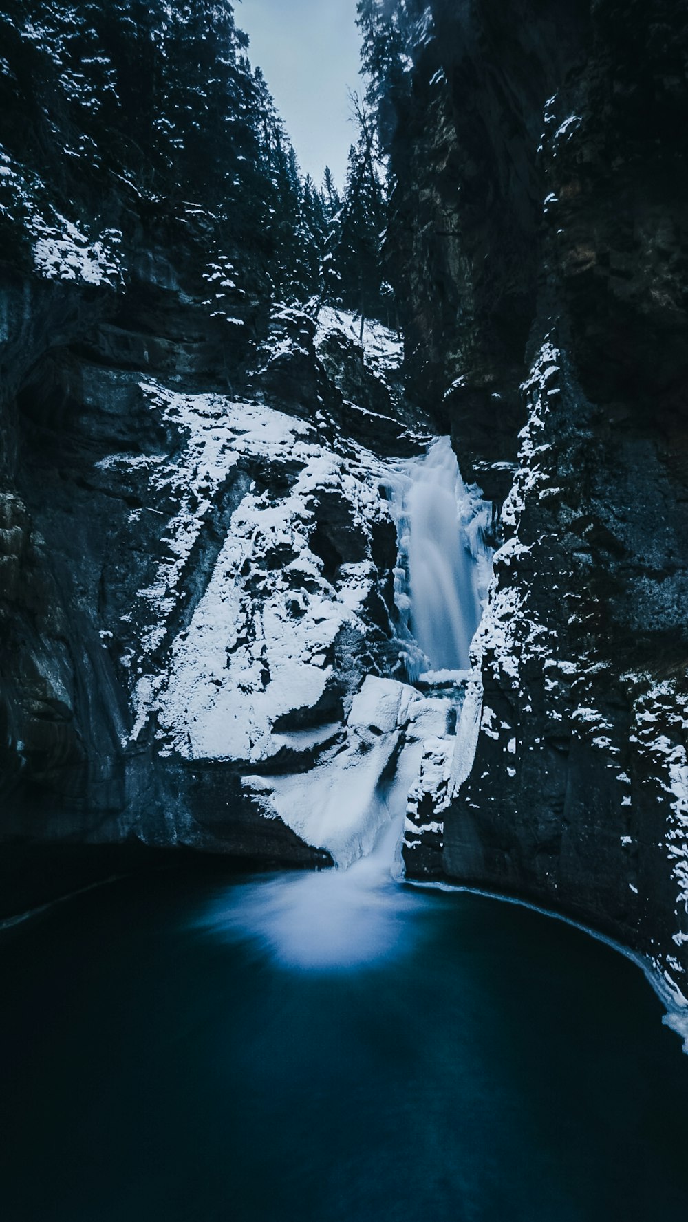 a waterfall in the middle of a snowy mountain