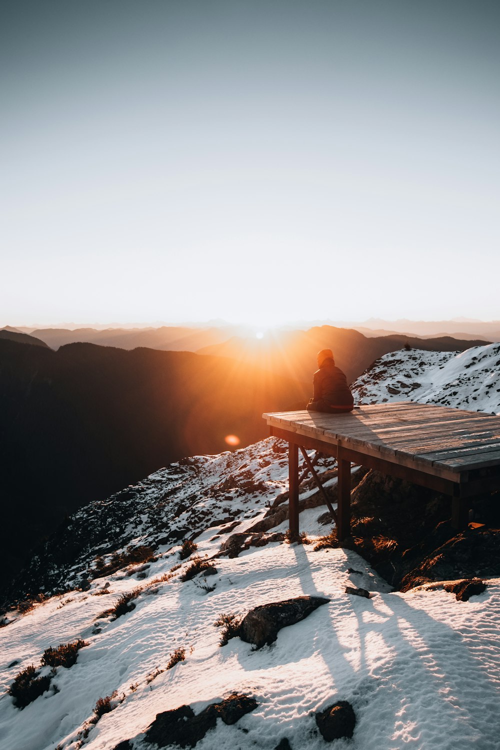 a person sitting on a bench at the top of a mountain