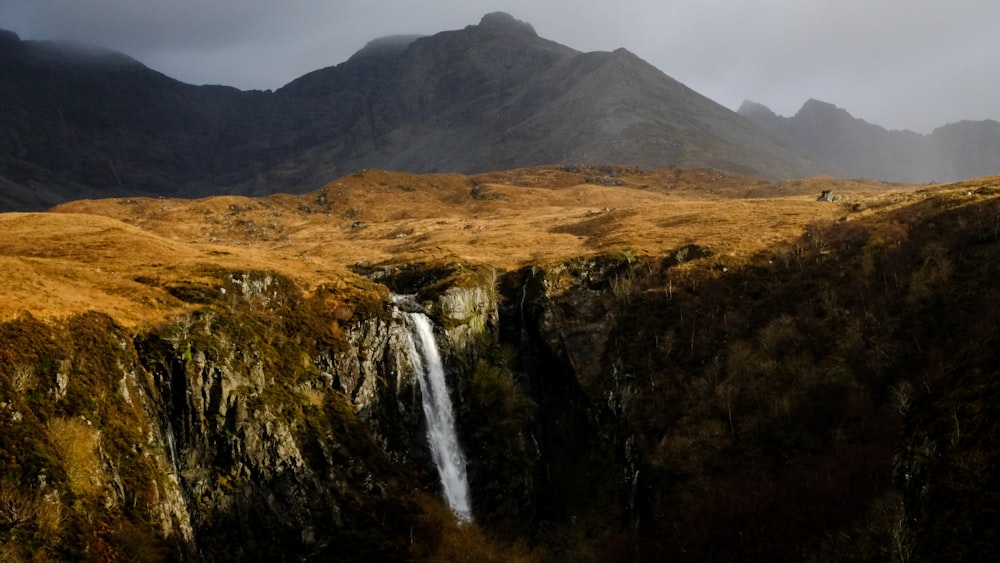 a waterfall in the middle of a mountain range