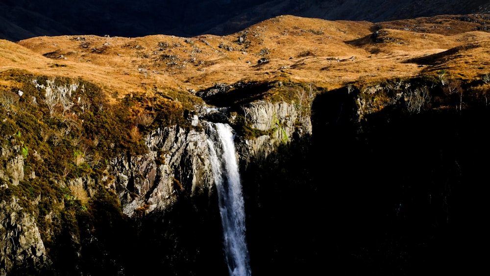 a small waterfall in the middle of a mountain range