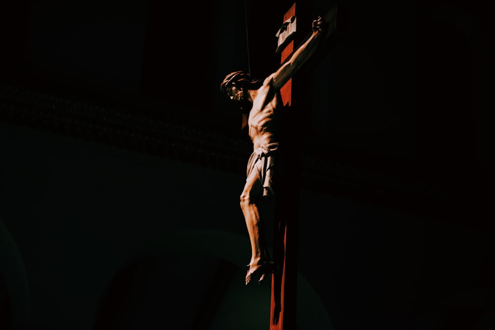 uma estátua de um homem em uma cruz no escuro