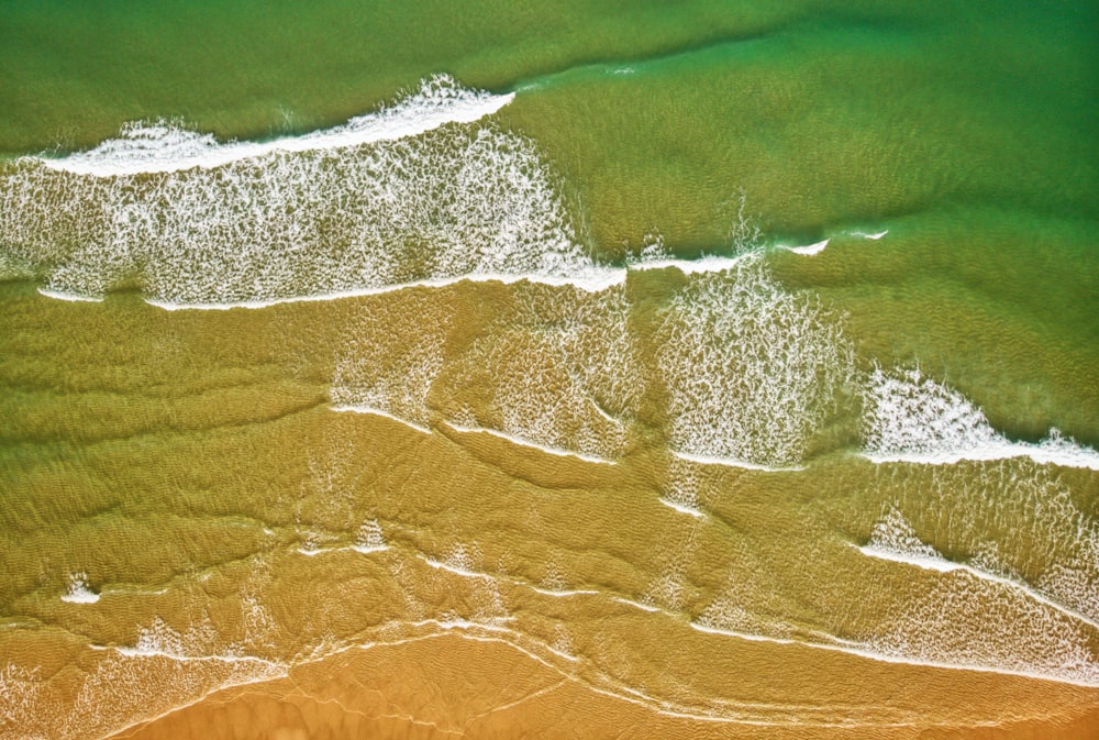 an aerial view of a beach with waves coming in