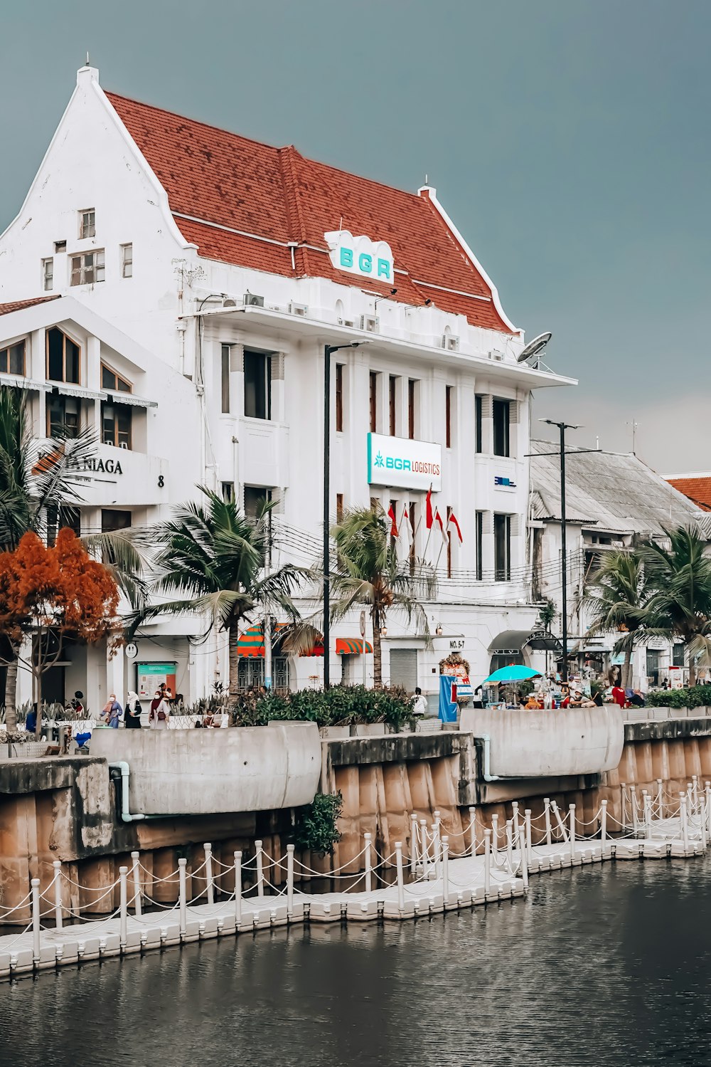 a white building with a red roof next to a body of water