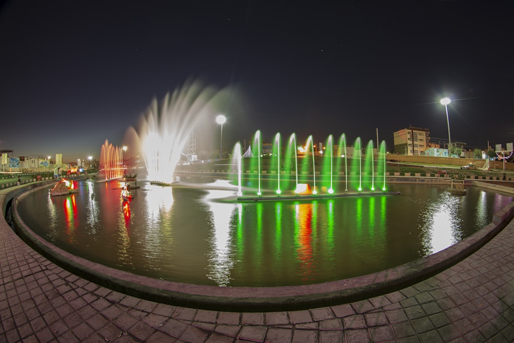 a colorful fountain is lit up at night