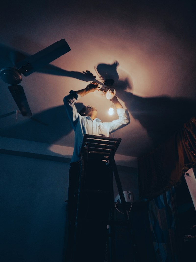 Maintenance technician repairing ceiling light fixture during scheduled visit