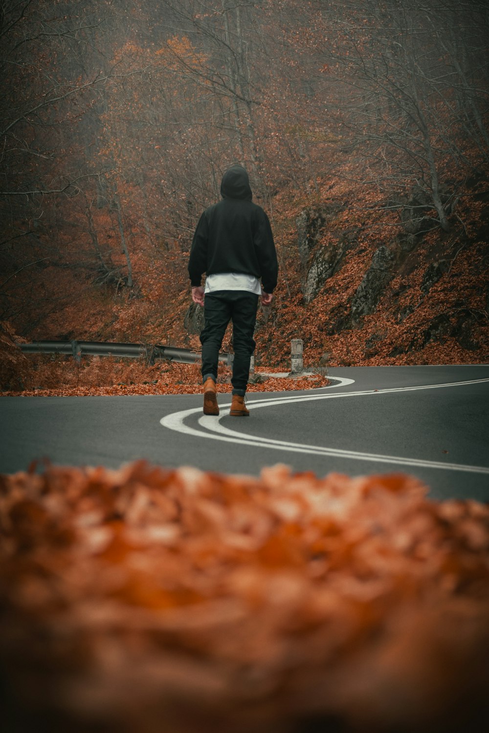 a man walking down a winding road in the woods