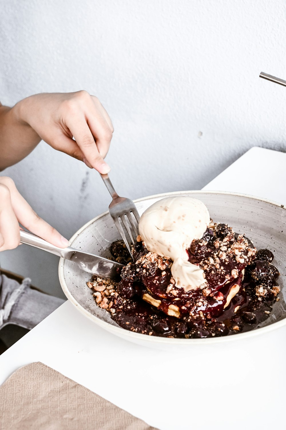 a person cutting into a bowl of food with a knife and fork