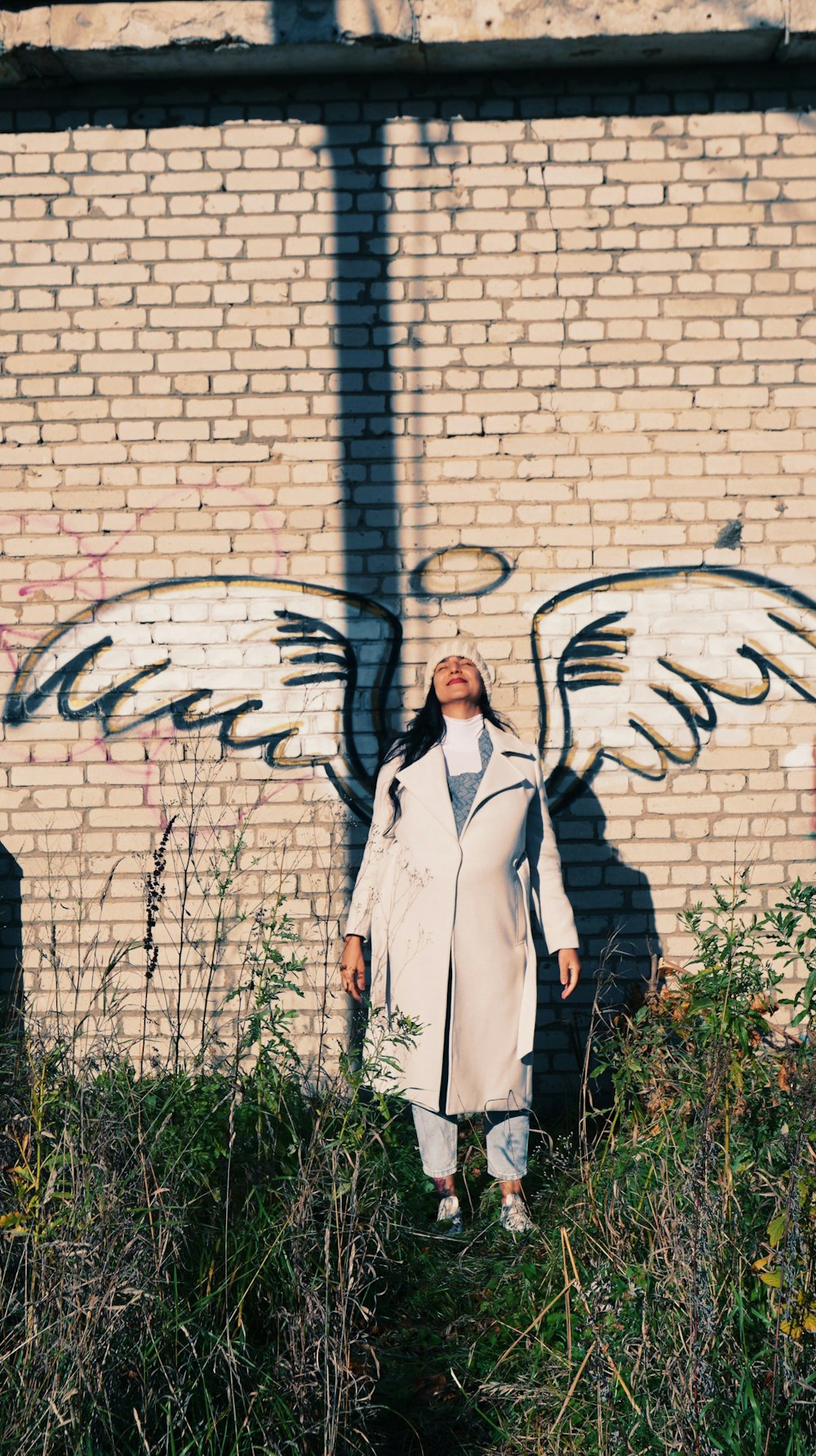 a woman standing in front of a brick wall