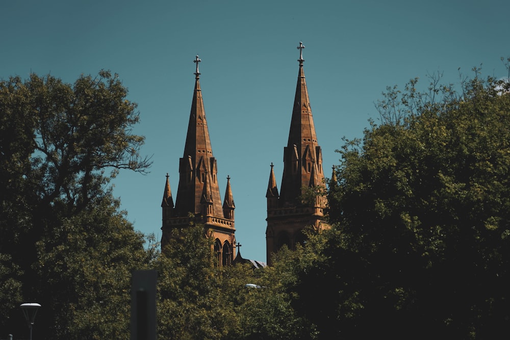two spires on top of a building surrounded by trees