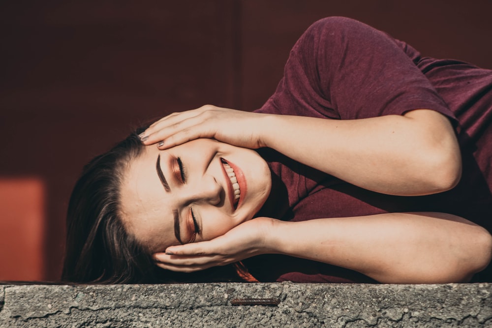 a woman with her eyes closed laying on a ledge