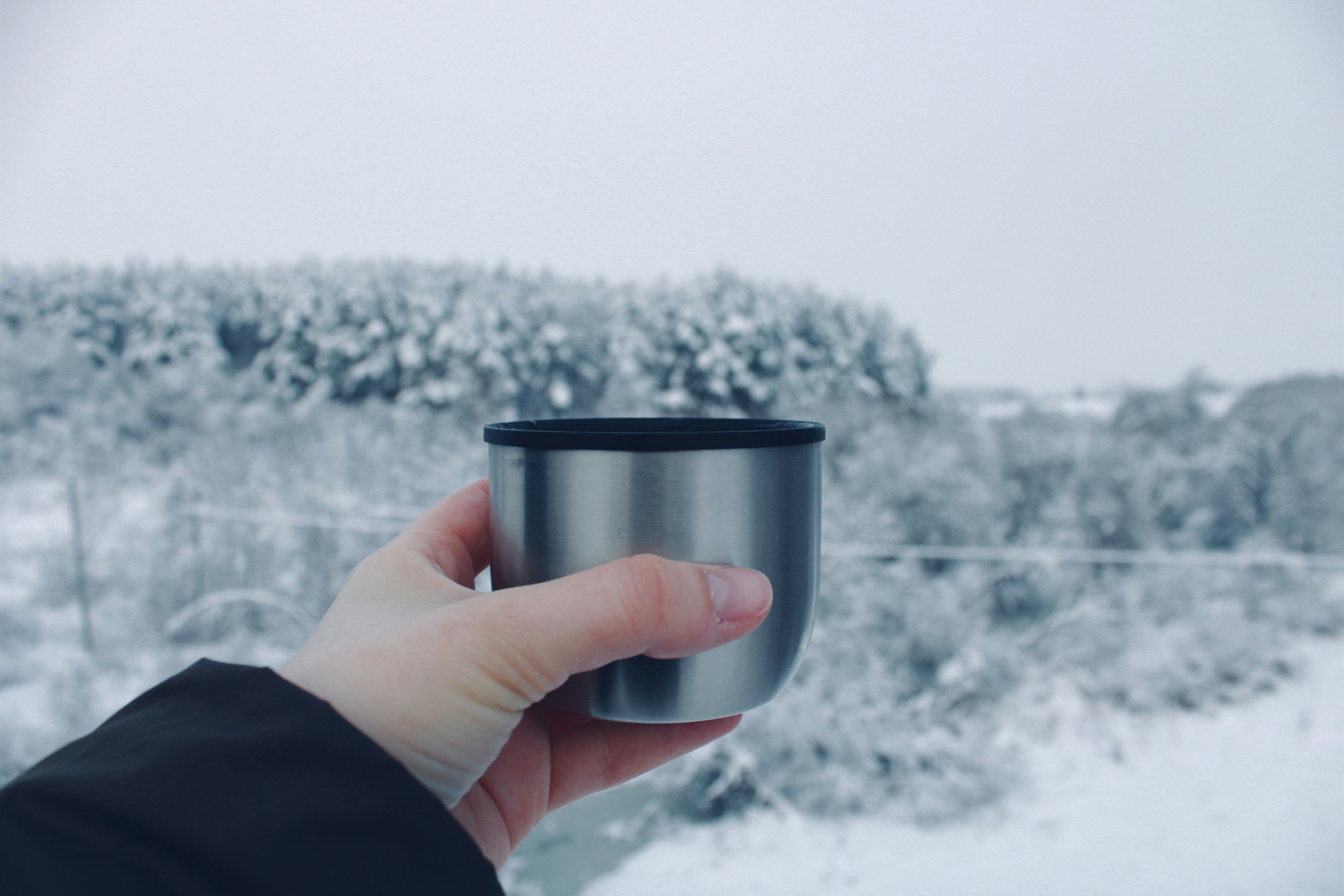 Person holding beverage bottle in snowy landscape