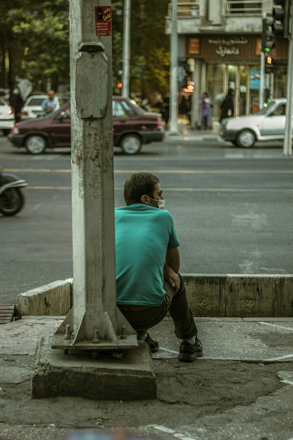 a man sitting on the side of a street next to a traffic light