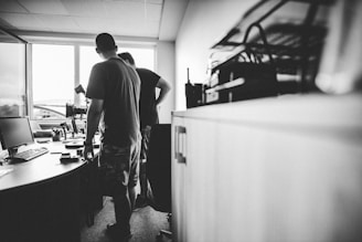 a man standing in front of a desk with a computer on it