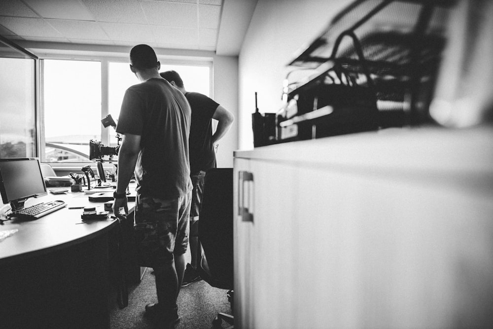 a man standing in front of a desk with a computer on it