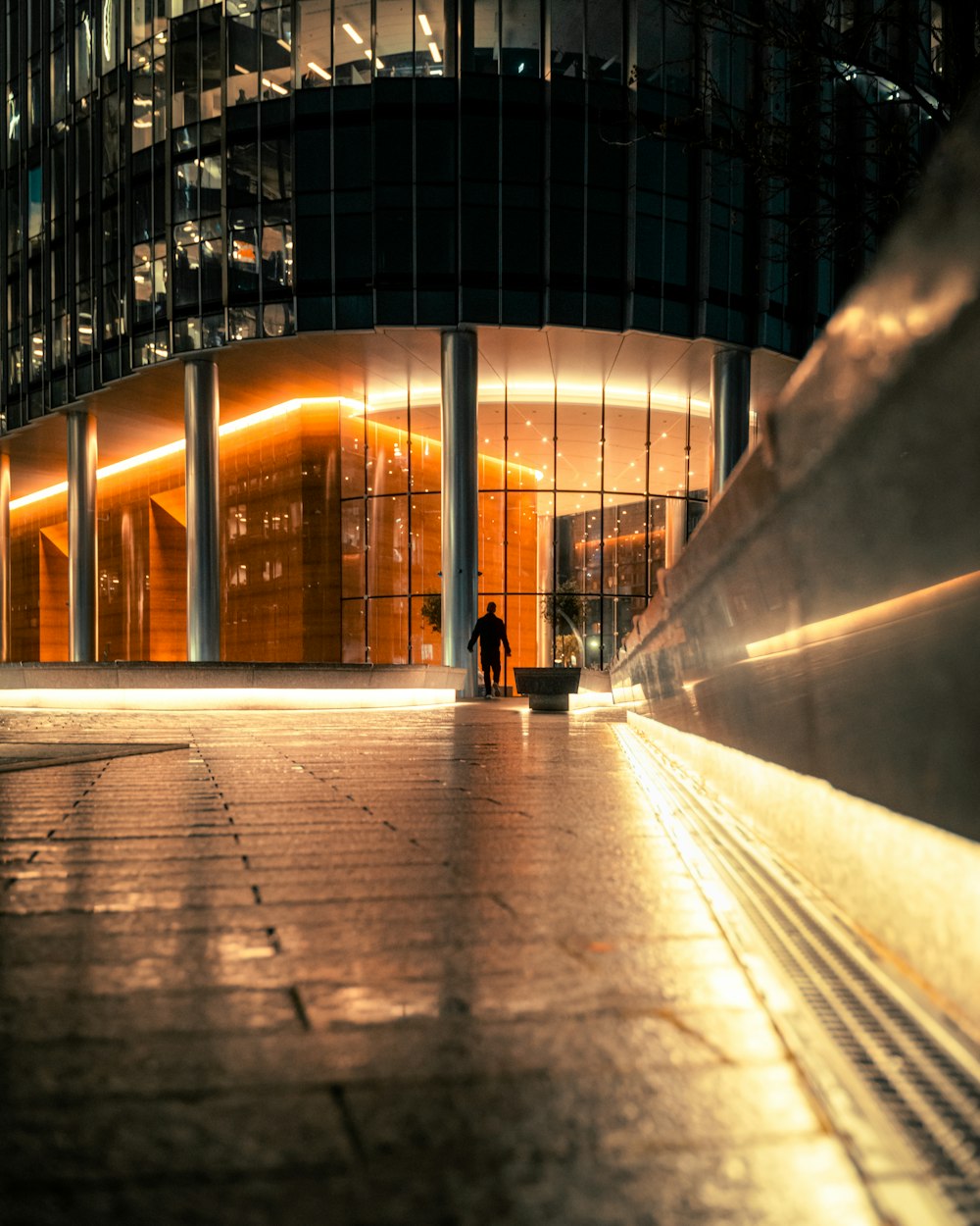 a man walking down a sidewalk next to a tall building