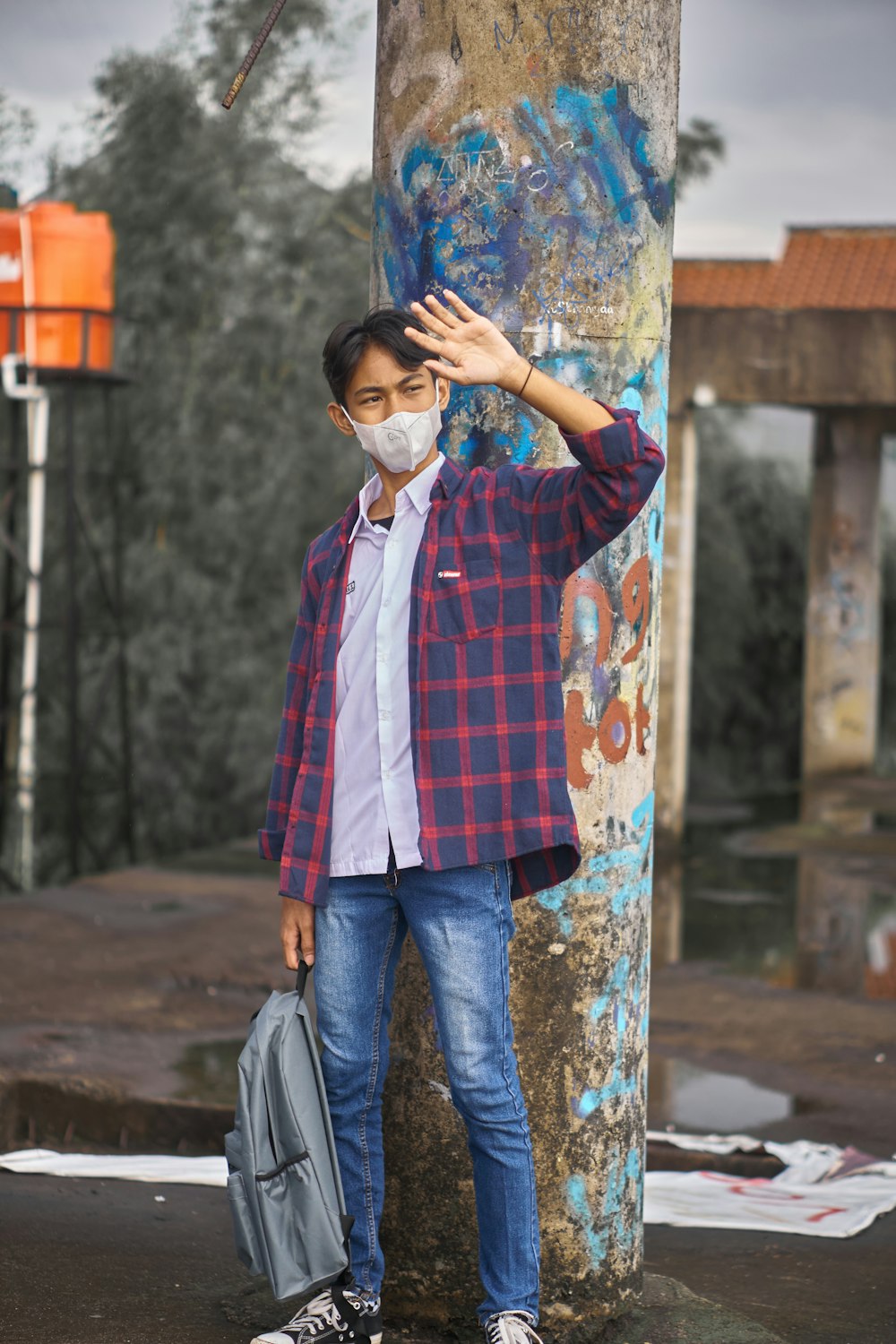 a man wearing a face mask standing next to a pole