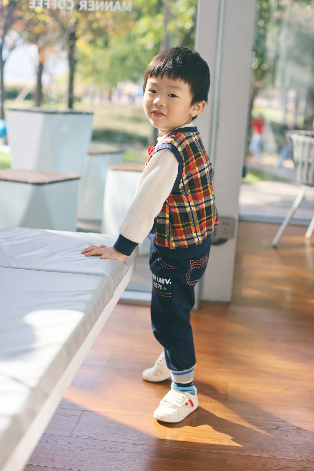 a little boy standing on top of a bed in a room