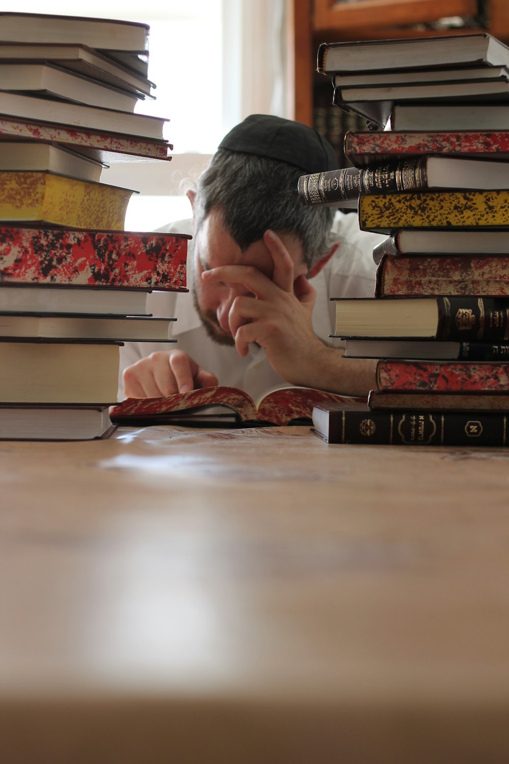 a man leaning his head on a stack of books