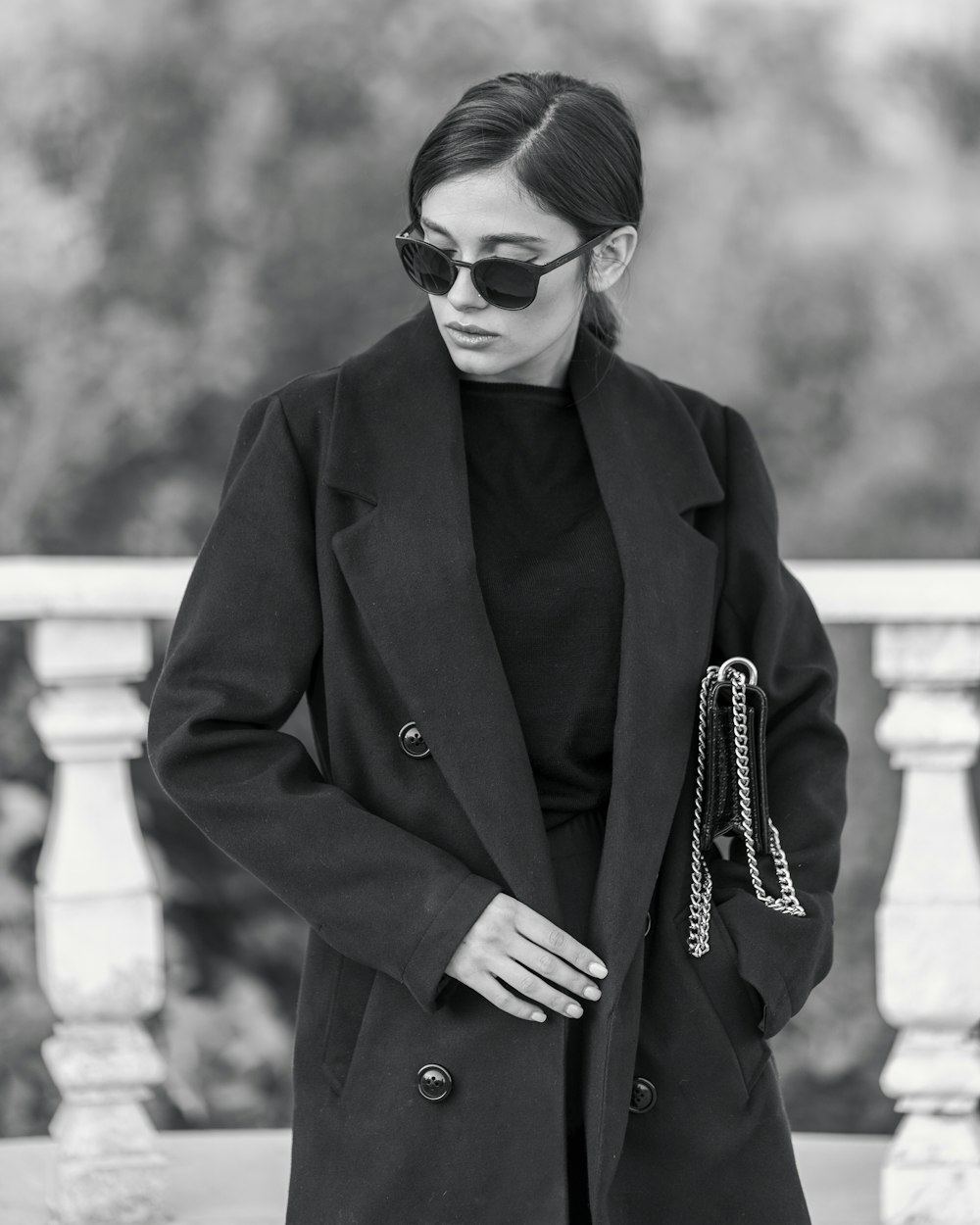 a woman in a black coat and sunglasses