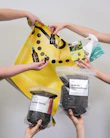 Hand holding eco-friendly garden tools with soil and plants in the background