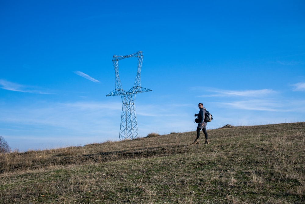 a man standing on top of a grass covered hill