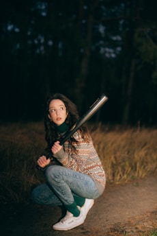 a woman kneeling down holding a baseball bat