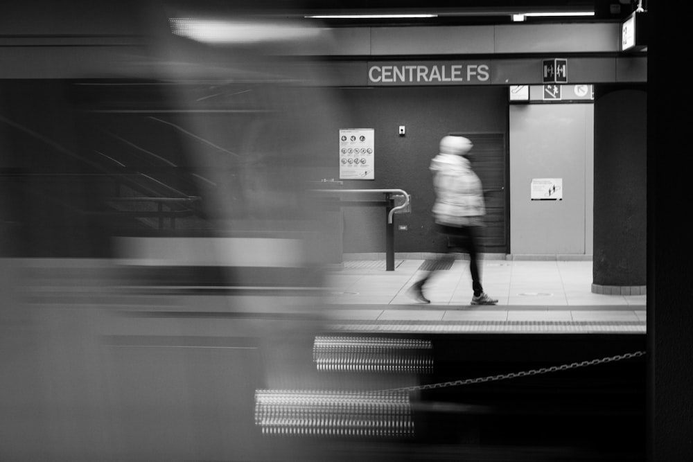 a blurry photo of a person walking past a train station