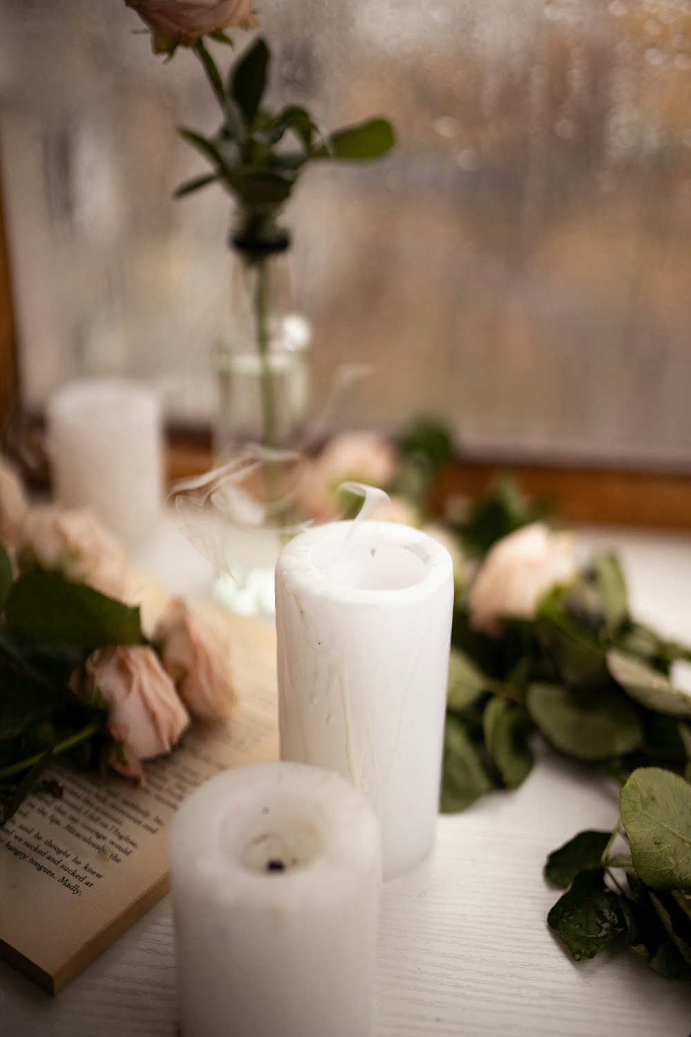a table topped with candles and flowers next to a window