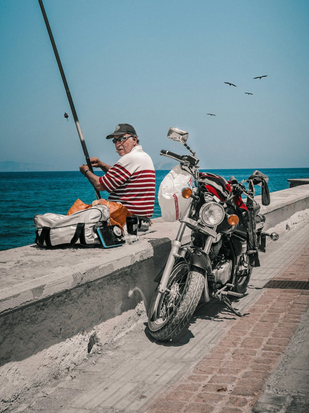 a man sitting on a wall next to a motorcycle