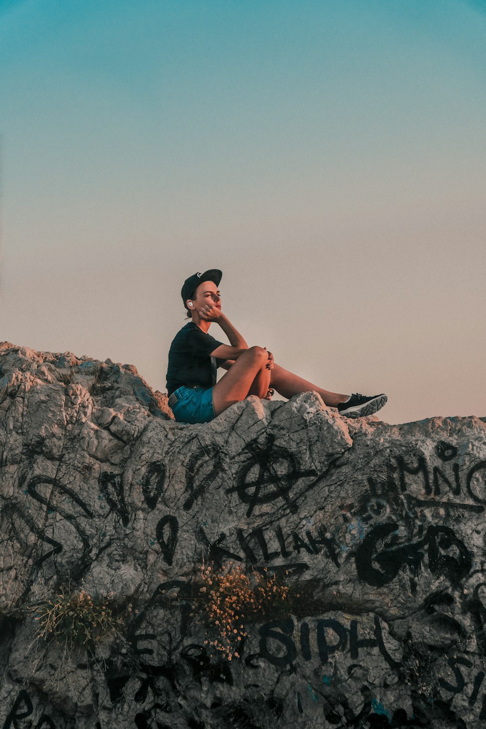 a man sitting on top of a rock covered in graffiti