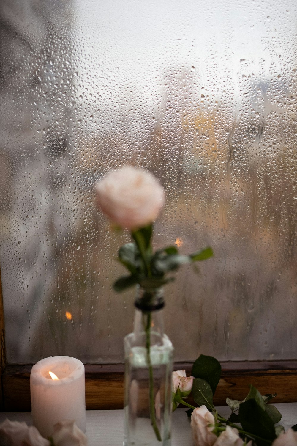 a vase with flowers and a candle on a window sill