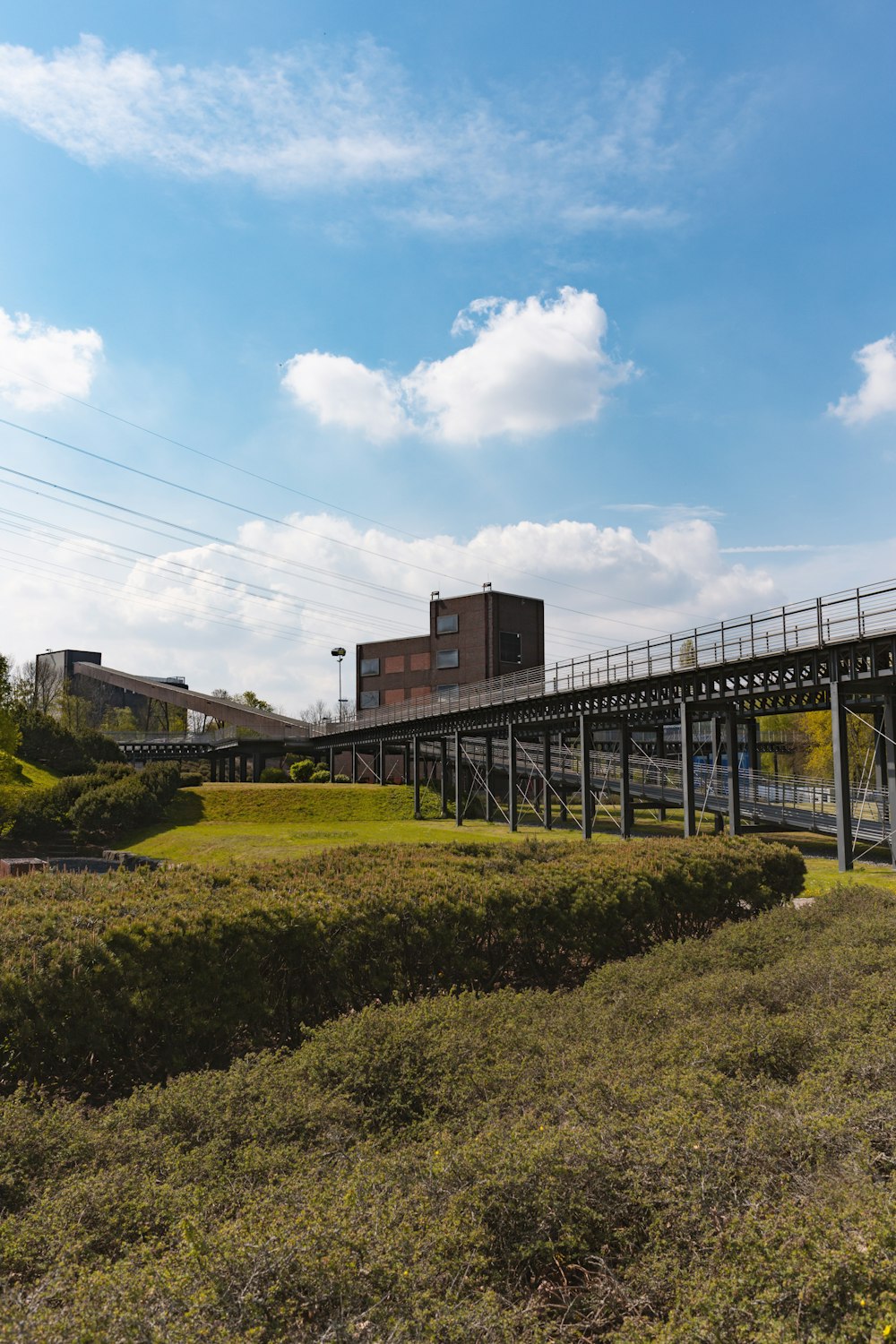 a train track going over a bridge over a lush green field