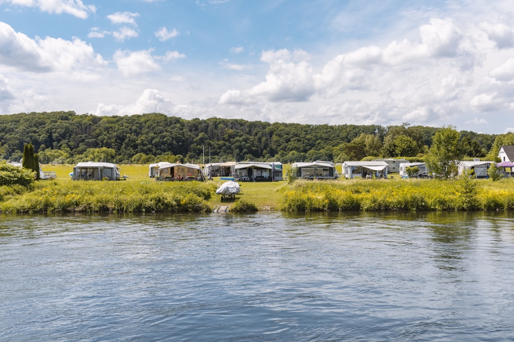 a group of tents sitting on top of a lush green field next to a river