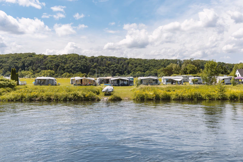 Tents on a grassy field beside a river