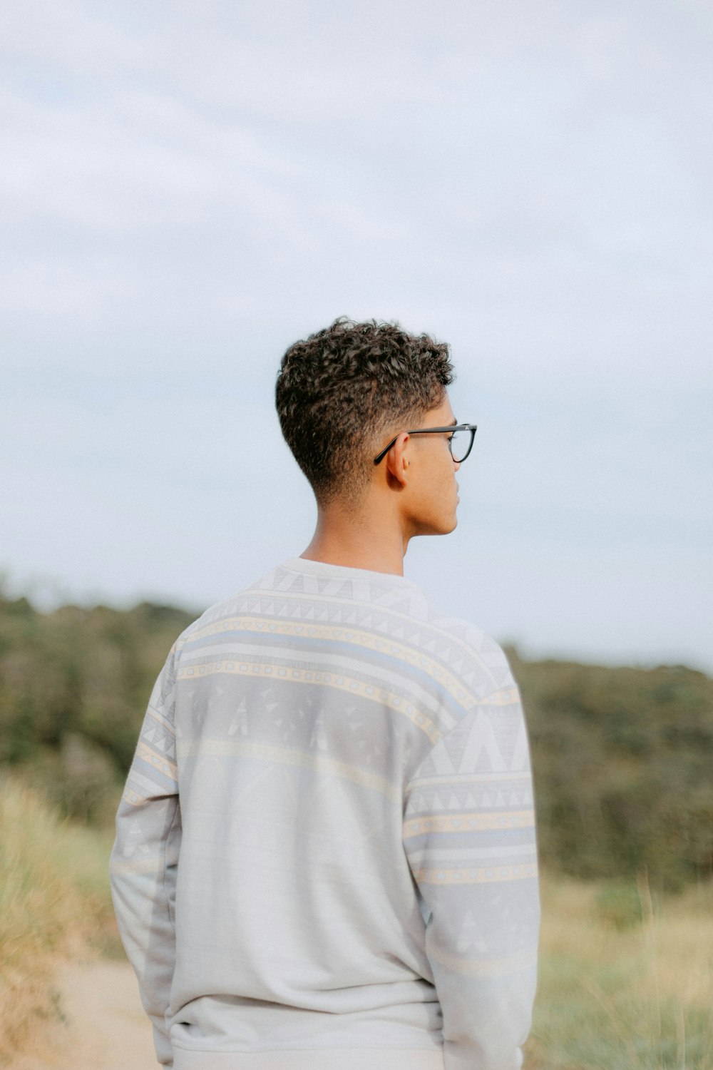 a man with glasses standing in a field