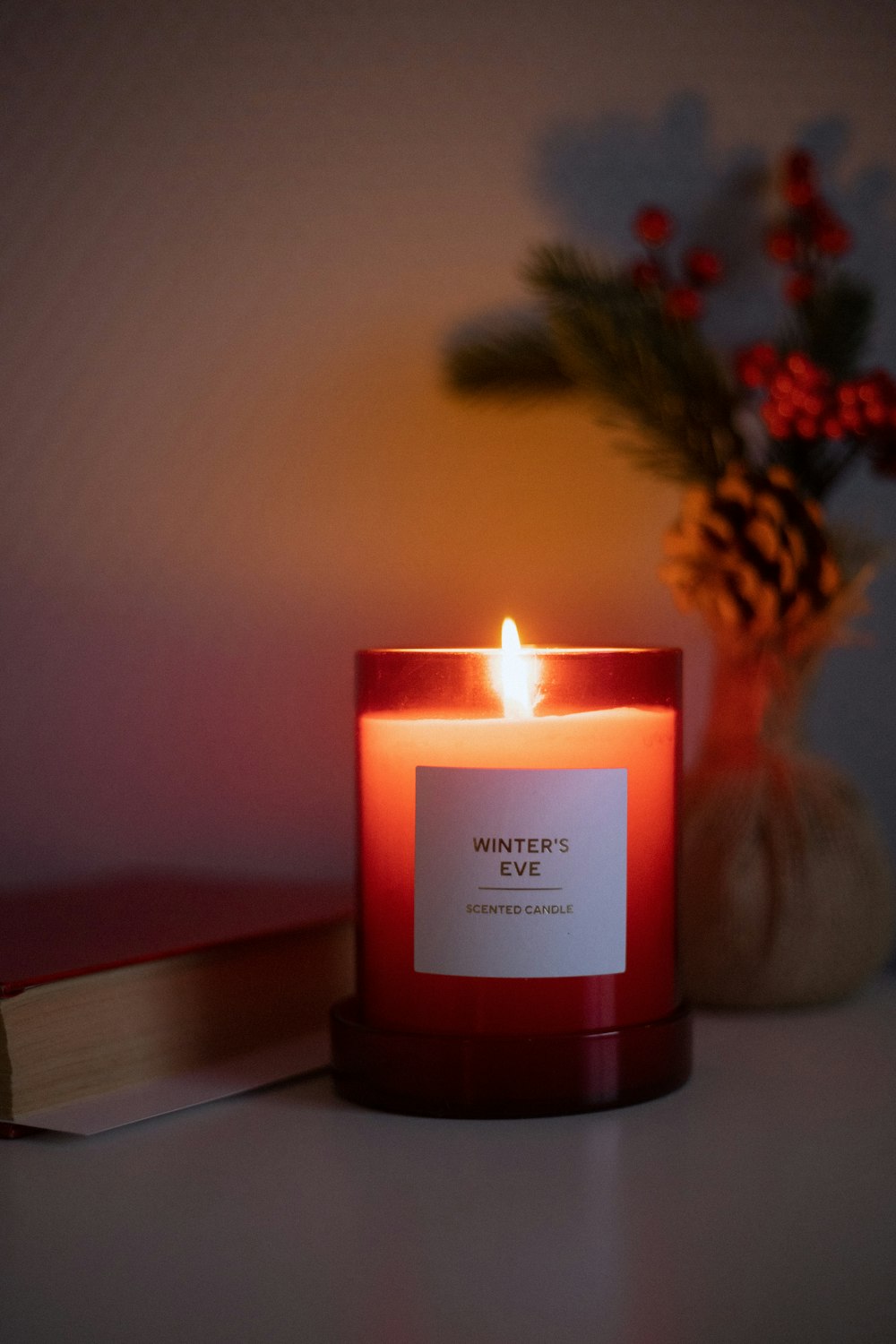 a red candle sitting on top of a table next to a book